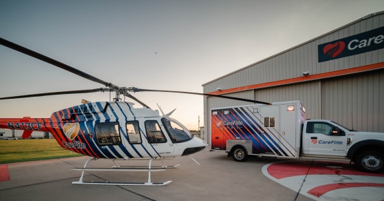 a white truck and helicopter on a runway